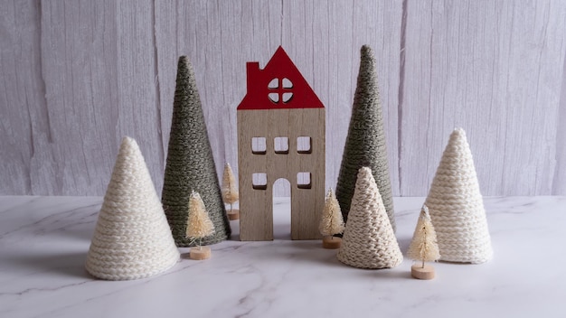 Maison en bois et arbres de Noël tricotés sur fond clair