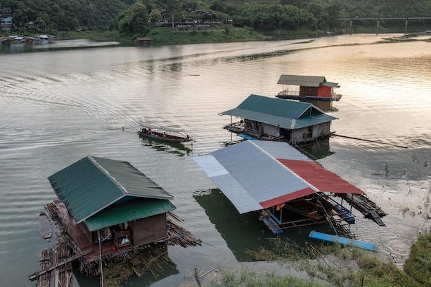 Maison en bois flottant sur barrage avec bateau de pêche