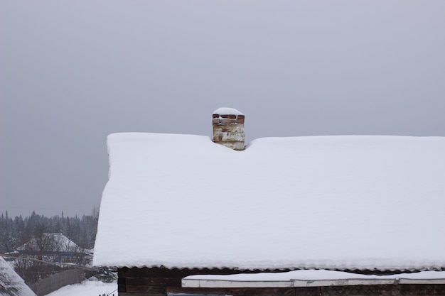 Photo maison en bois en hiver dans la neige. une maison avec une cheminée et un poêle.