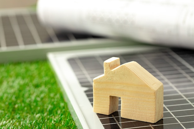 Photo maison en bois miniature et panneau solaire se bouchent