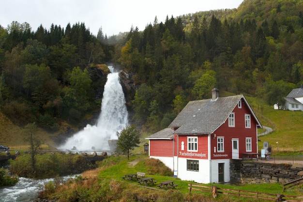 Maison en bois norvégienne traditionnelle et cascade au loin