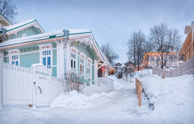 Maison en bois avec plateaux ajourés à Plyos dans la neige à la lumière du soleil d'hiver couchant