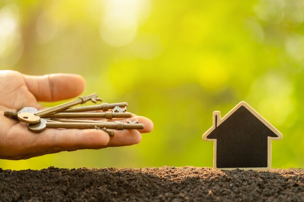 Maison en bois poussant dans le sol et clé vintage sur fond de flou de nature verte. Clé du succès du concept de croissance d'entreprise à domicile