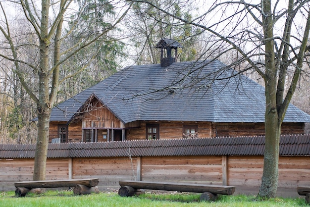 Une maison en bois avec un toit noir et une clôture en bois.