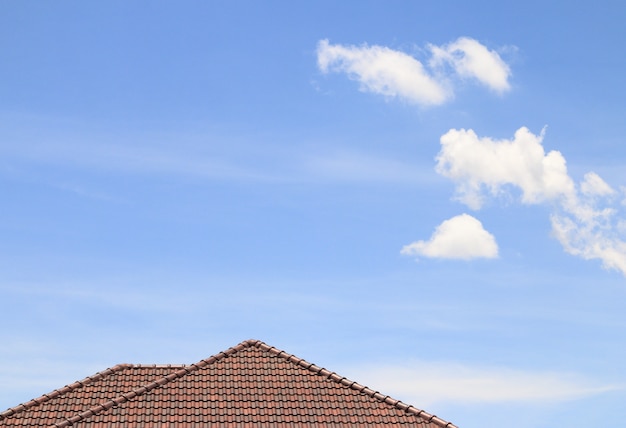 Maison brique brun toit, ciel bleu et fond de nuage.