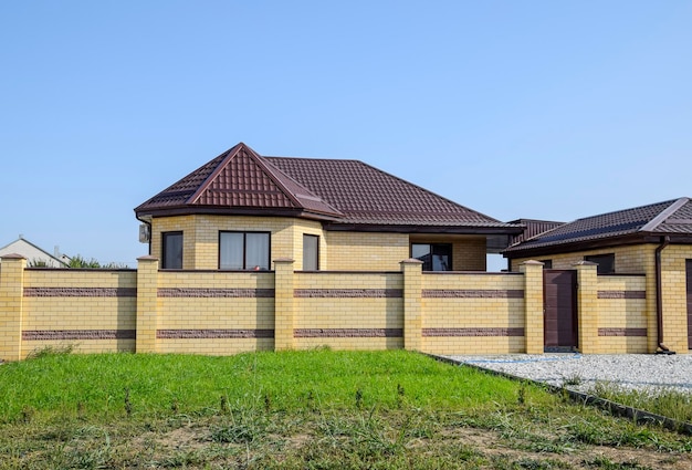 Maison en brique avec clôture et portes Vue d'une nouvelle clôture construite et d'une maison en briques et tôle ondulée