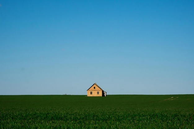 Maison sur un champ vert et un ciel bleu