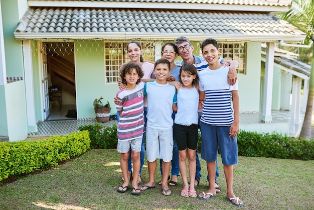 Cette maison a construit trois générations de souvenirs de famille Portrait d'une famille multigénérationnelle heureuse se tenant ensemble dans leur arrière-cour