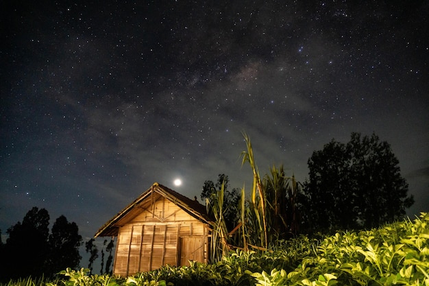 Une maison dans le ciel nocturne avec la voie lactée en arrière-plan