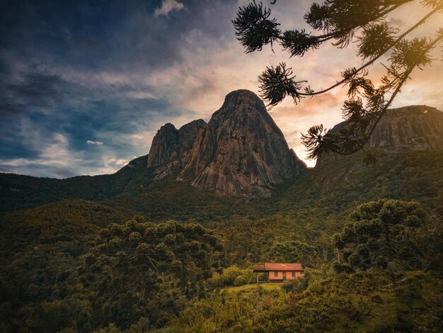 Photo une maison dans les montagnes avec un ciel nuageux en arrière-plan