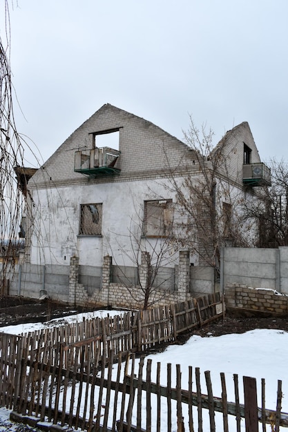 Une maison dans la neige avec un balcon et une clôture au premier plan.