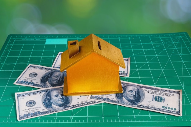 Maison dorée avec billet de banque en dollars, concept immobilier.