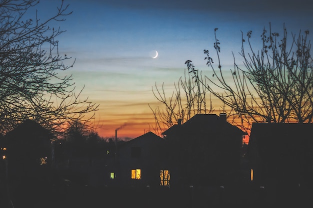 Photo maison du soir à l'ombre et au jeune mois.