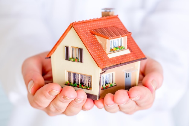 Maison entre des mains humaines sur fond blanc