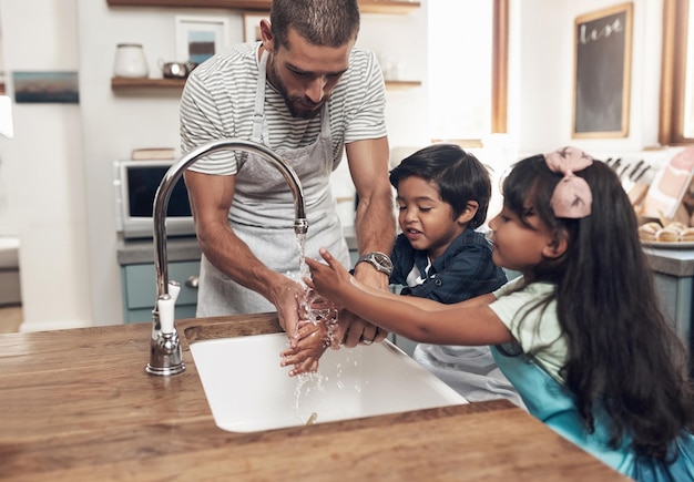 La maison est l'endroit où vous êtes le plus aimé et où vous agissez le pire Photo d'un homme et de ses deux enfants se lavant les mains dans le lavabo de la cuisine