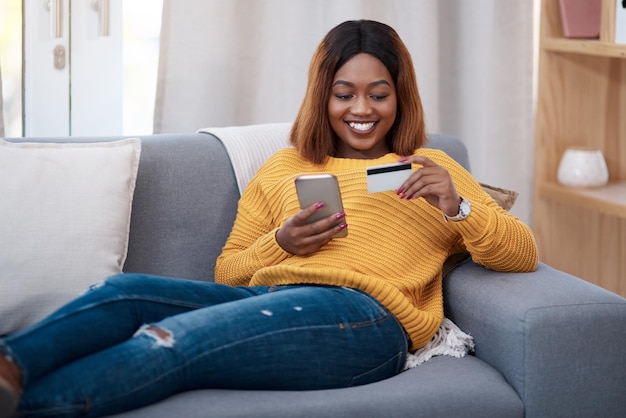 La maison est mon endroit heureux Photo d'une jolie jeune femme utilisant une carte de crédit tout en naviguant en ligne