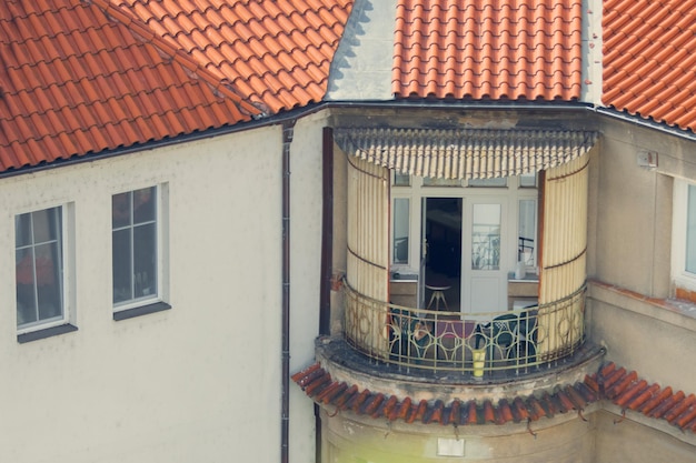 Maison avec une façade blanche, un toit en tuiles rouges et un balcon