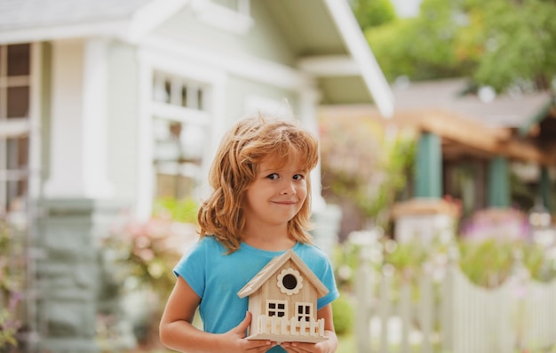 Maison familiale protégeant le concept d'assurance maison dans les mains des enfants enfant garçon construction maison soins enfant heureux