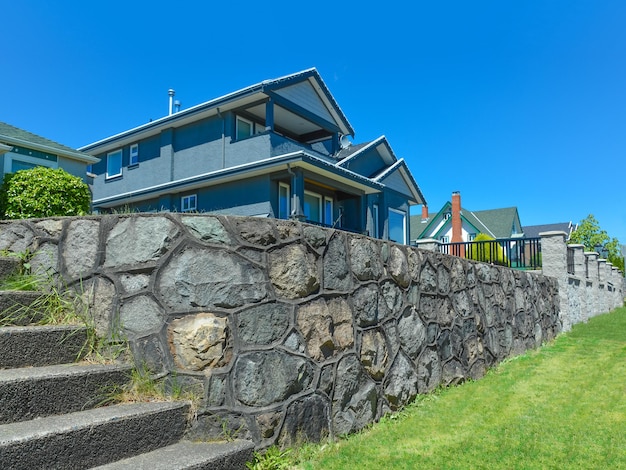 Maison d'habitation sur terrain terrasse avec escalier menant à la cour avant