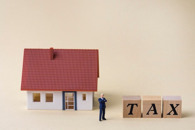 Photo maison et homme miniature avec mot fiscal écrit en cubes de bois