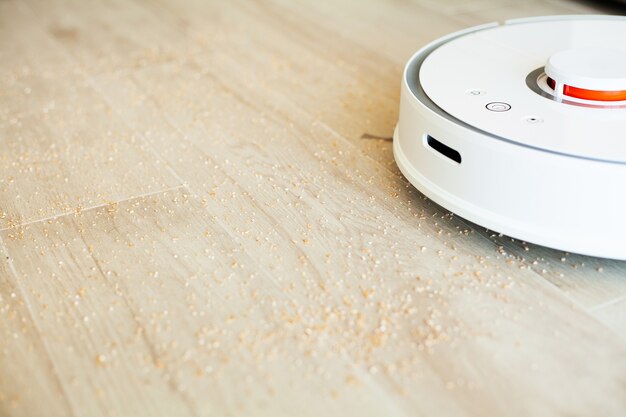 Maison intelligente. Robot aspirateur fonctionne sur plancher en bois dans un salon