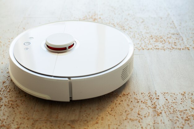 Maison intelligente. Robot aspirateur fonctionne sur plancher en bois dans un salon