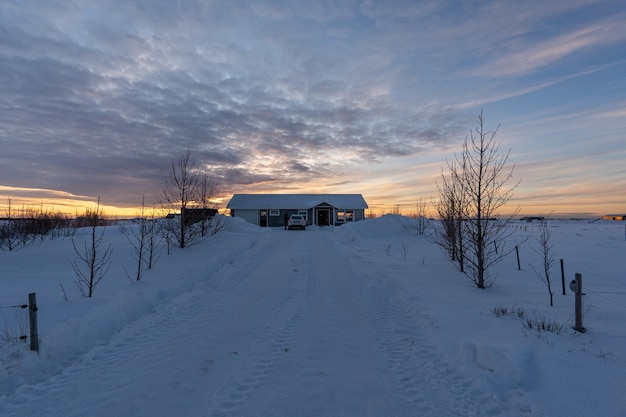 Maison isolée dans la neige avec le sol et la route entièrement enneigés dans un quartier résidentiel