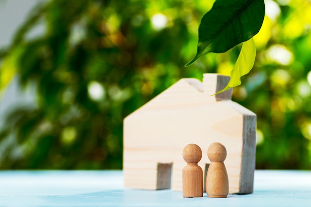 Maison de jouet en bois et famille en bois sur fond de feuillage se bouchent