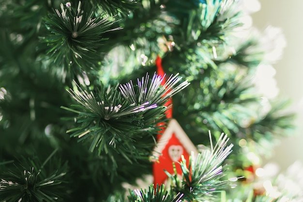 Maison de jouet en bois rouge sur les branches d'arbres de Noël décorées