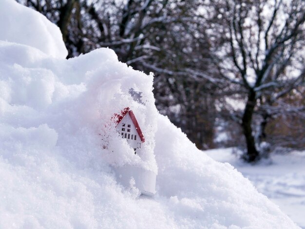 Maison de jouet sur fond de neige hiver le concept de confort à la maison