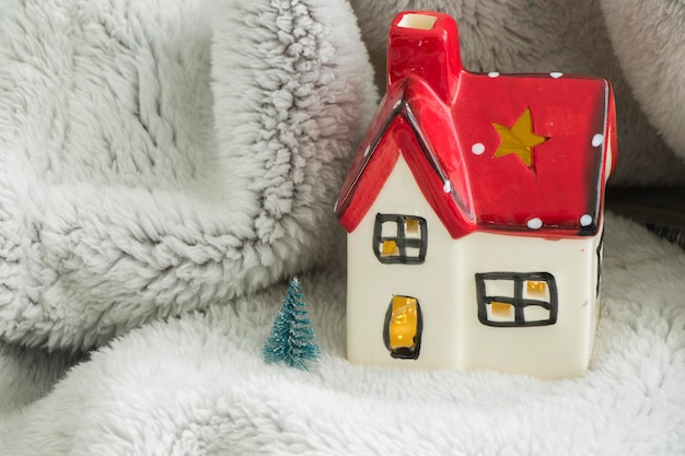 Photo maison de jouet avec toit rouge, pin et neige. décoration du nouvel an. l'esprit de noël.