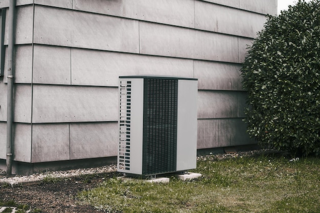 Une maison avec une maison blanche et une pompe à chaleur dans la cour Concept d'un système de chauffage rentable