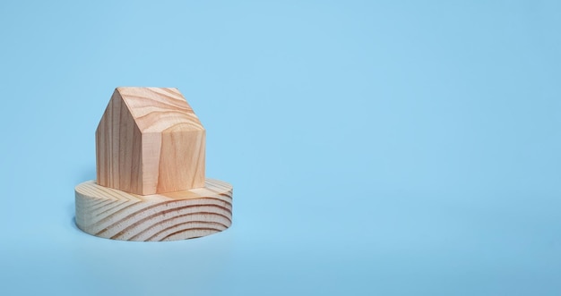 Maison miniature et blocs de bois sur fond bleu clair