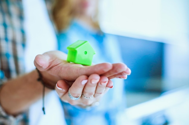 Maison modèle à la main d'un couple debout dans une nouvelle maison