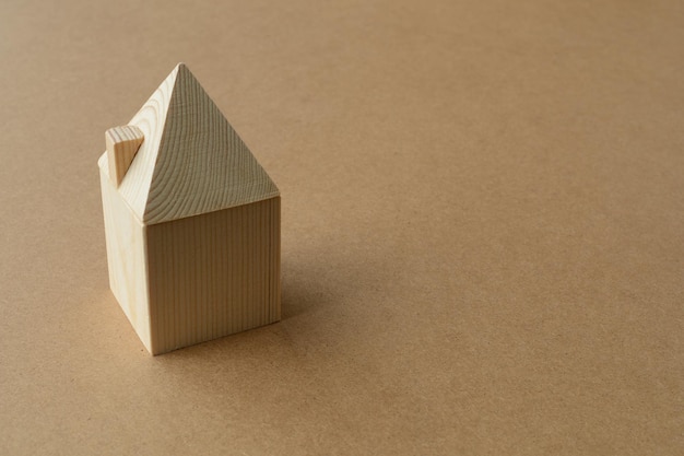Maison modèle miniature faite de poutres en bois sur fond de carton. Construction, concept d'hypothèque