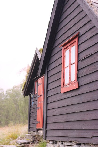 Une maison noire avec une fenêtre rouge dans le coin.