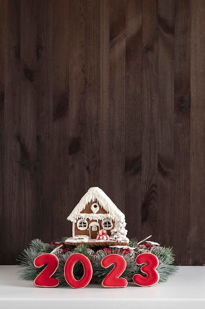 Maison en pain d'épice et Inscription 2023 Joyeux Noël fond copie espace Cadre vertical Mur en bois foncé sur fond