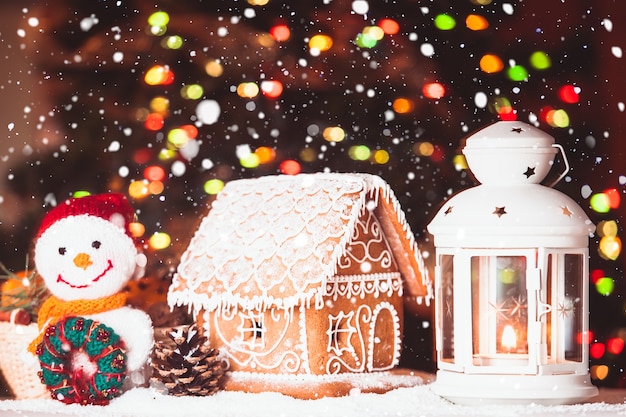 Maison de pain d'épice sur la neige, bonhomme de neige et chandelier