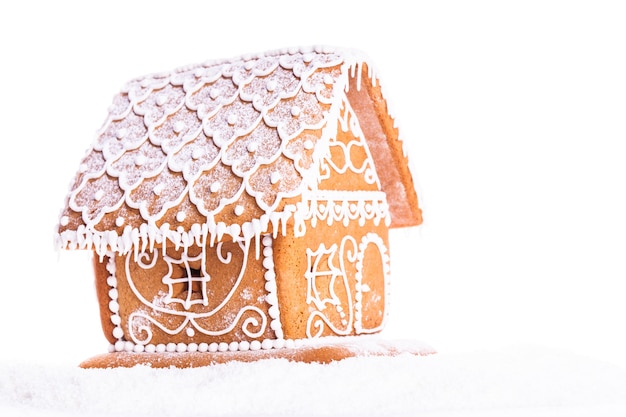 Maison en pain d'épice sur une neige sur fond blanc