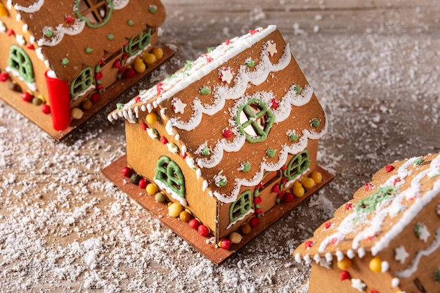 Maison en pain d'épice de Noël décorée de bonbons et de glaçage sur table en bois