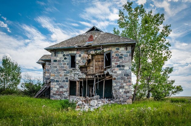 Une maison en pierre abandonnée entourée d'arbres dans les prairies de la Saskatchewan à l'extérieur d'Abernethy, SK