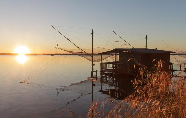 Photo maison sur pilotis dans le lac contre le ciel au coucher du soleil