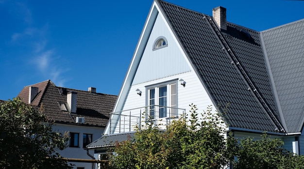 Une maison privée de deux étages avec un toit triangulaire et une zone près de la maison contre un ciel bleu