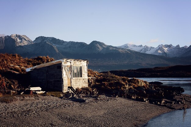 Maison sur la rivière avec les montagnes à l&#39;arrière.