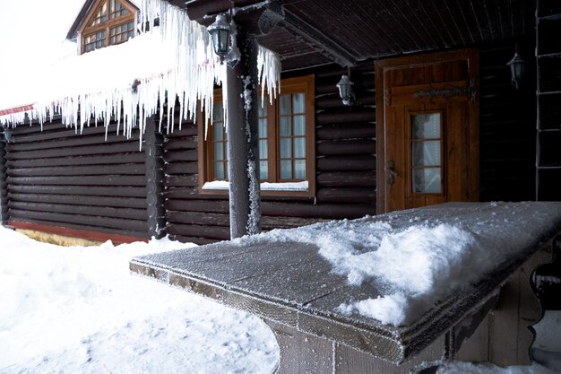 La maison en rondins avec le toit glacé et les glaçons suspendus