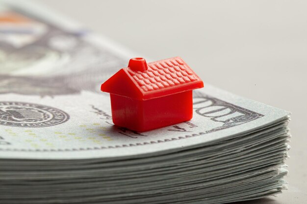 Maison rouge sur une pile d'argent Le concept de taxes ou de prêts immobiliers