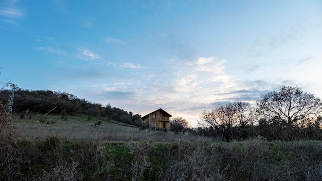 Maison de village en bois à deux étages dans un terrain rempli d'herbe sèche