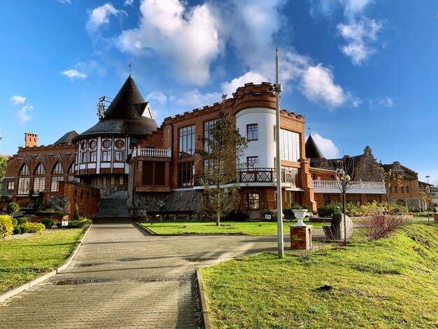 Maison vintage dans un parc verdoyant avec un ciel bleu nuageux