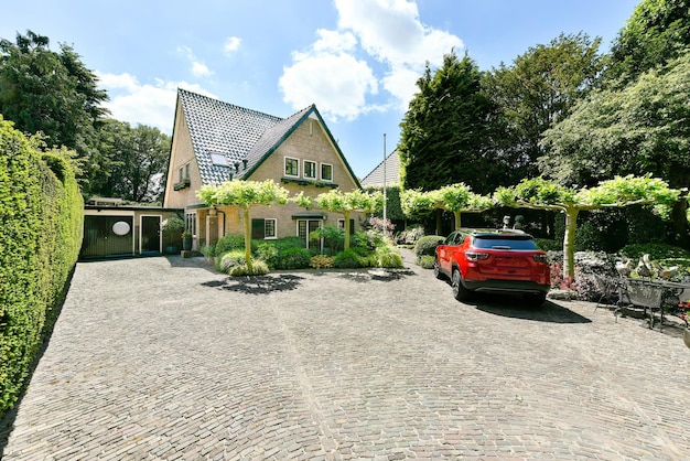 Une maison avec une voiture rouge garée dans une allée