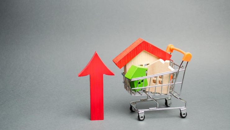 Photo des maisons en bois dans un chariot d'achat et une flèche rouge font ressortir le concept d'augmentation du coût du logement